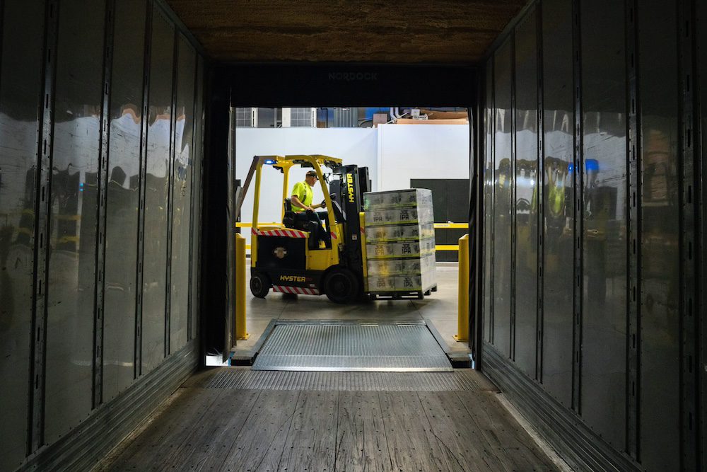A forklift moves stacks of boxes inside a warehouse.