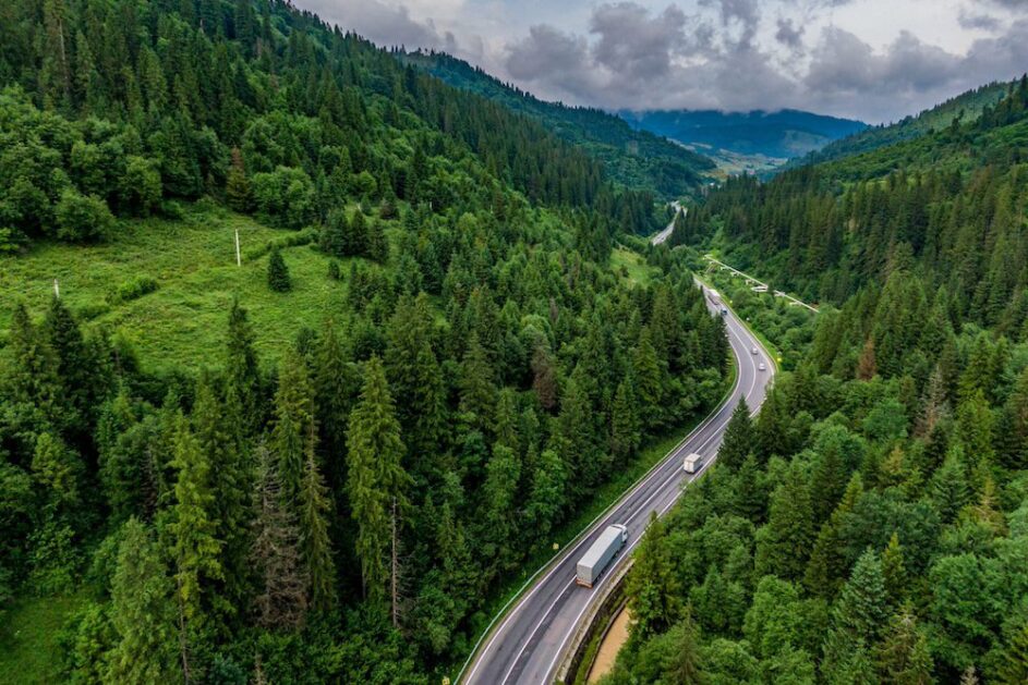 Ariel view of a delivery truck driving on a highway through the mountains, calling attention for the need to consider scope 3 emissions as it relates to shipping and deliveries