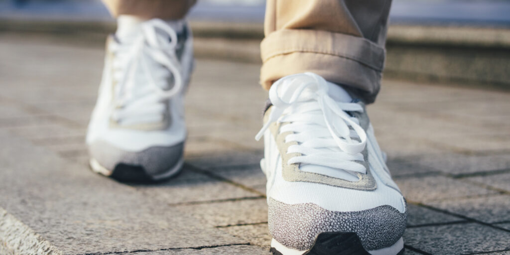 A non-descript pair of sneakers walking down a stone path