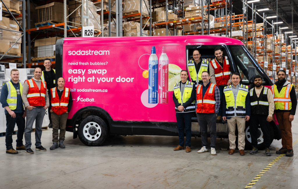 GoBolt and SodaStream executives standing in front of a hot pink Sodastream-branded electric delivery vehicle